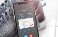 Graphic of a running app on a phone leaning on a running shoe.