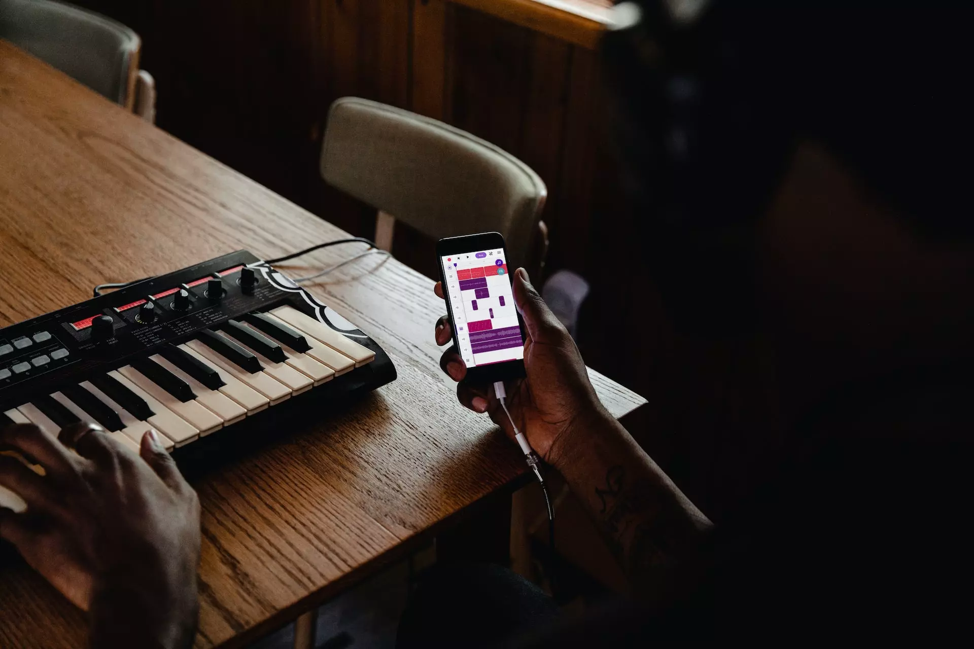 Person holding a phone connected to a digital piano