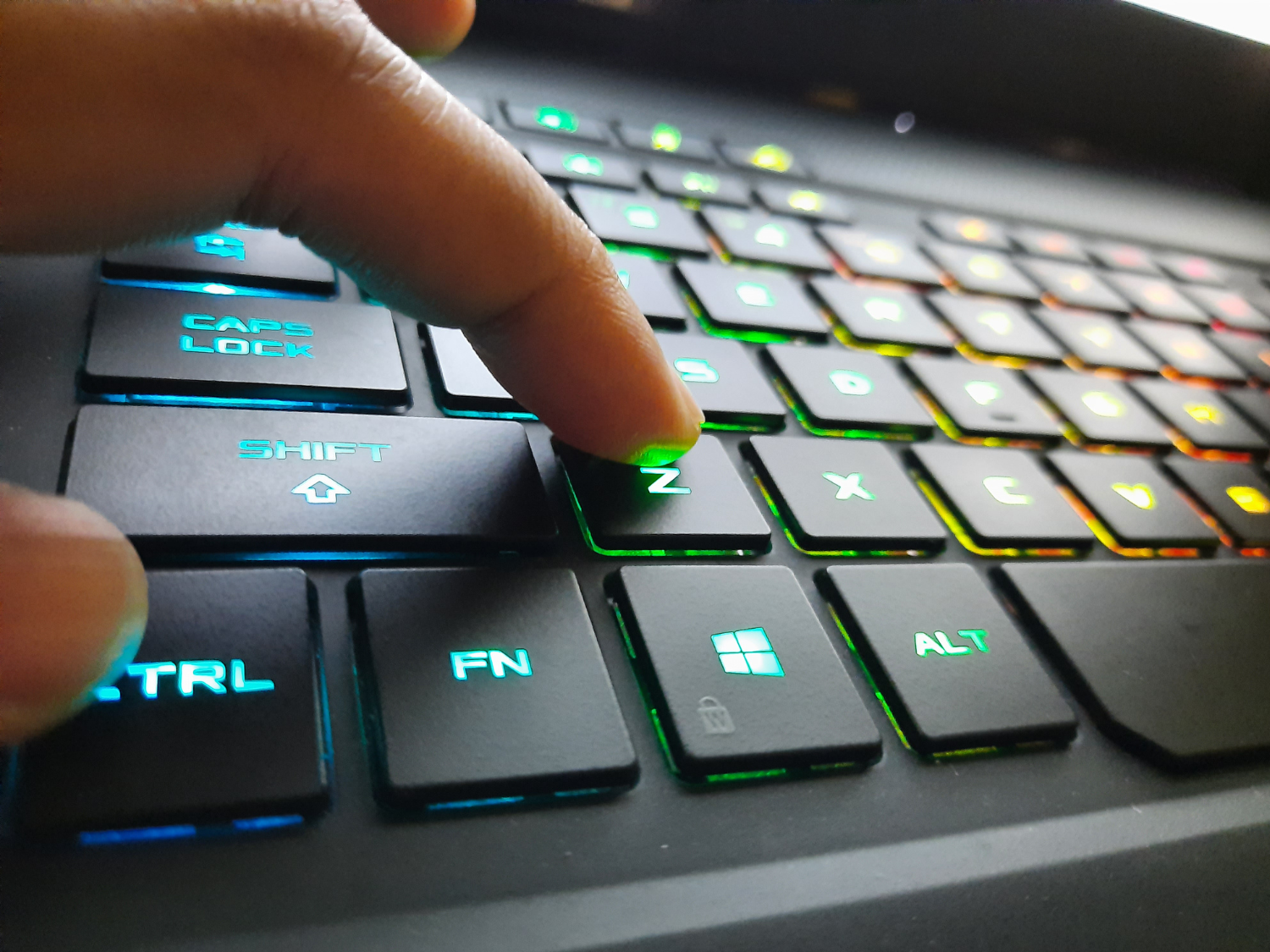 A computer keyboard with a finger on a key
