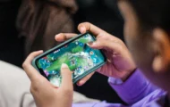 Person playing a mobile multiplayer game on a smartphone held horizontally.